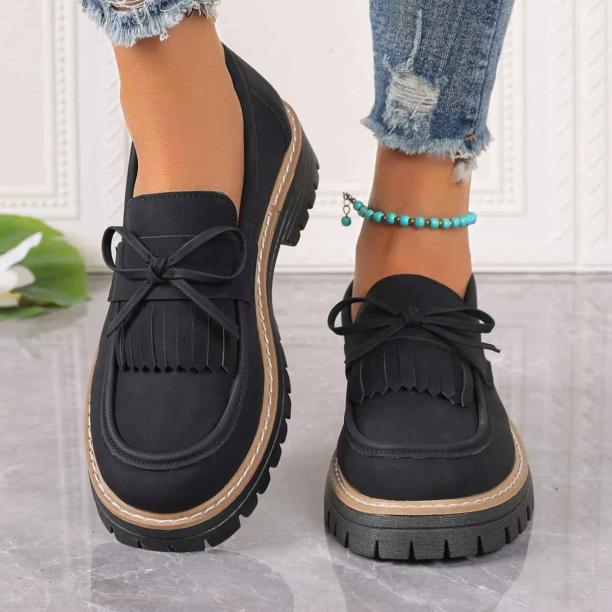 Plus size women's black loafers with a tassel and bow knot detail on the upper.
