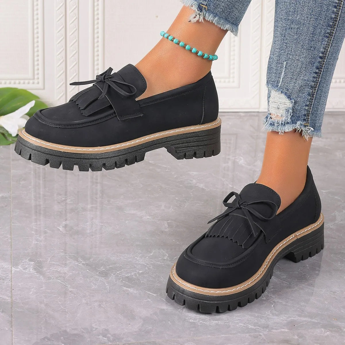 Plus size women's black loafers with a tassel and bow knot detail on the upper.