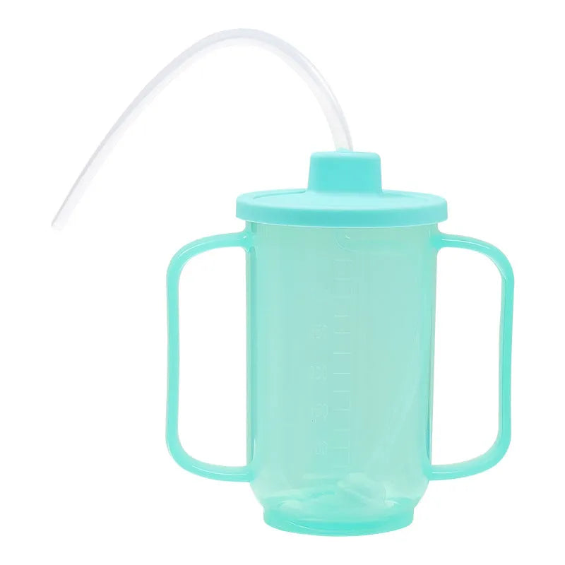 Adult bedside drinking cup with angled choke-proof mouth, handle, and lid, shown in care setting.