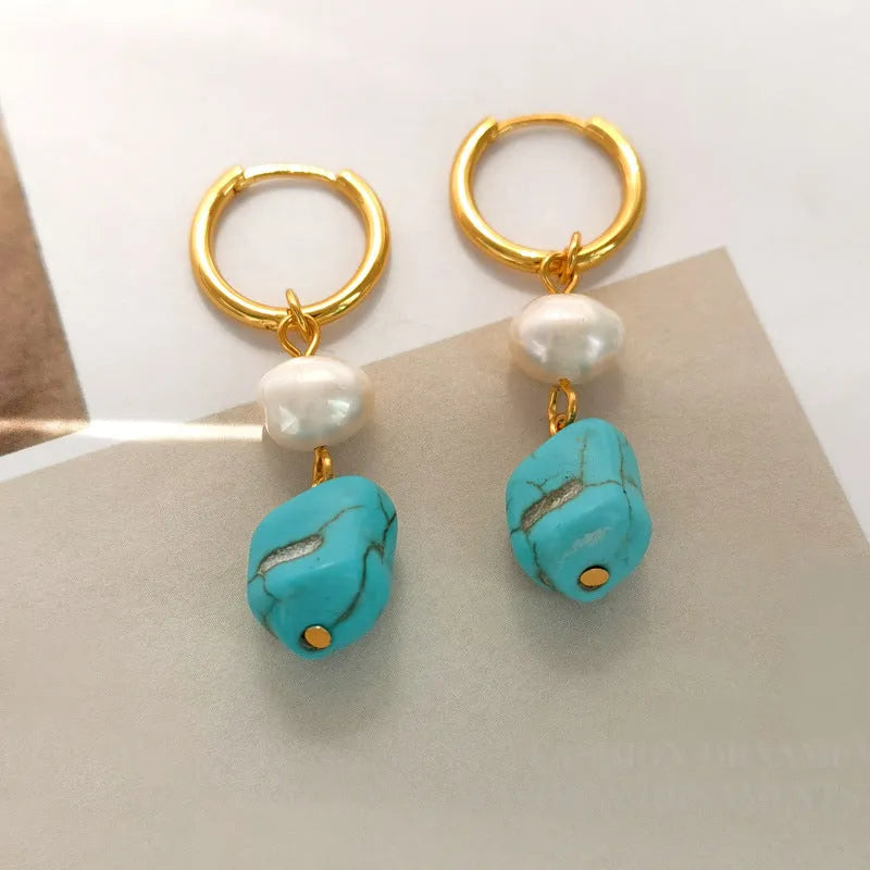 A pair of women's geometric drop earrings with irregular turquoise stones and round cultured pearls on copper settings.