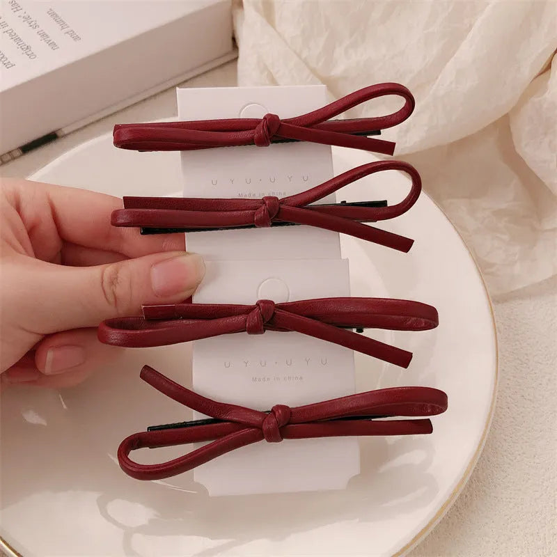 Wine red leather bow hair barrette on hair, showing single clip design