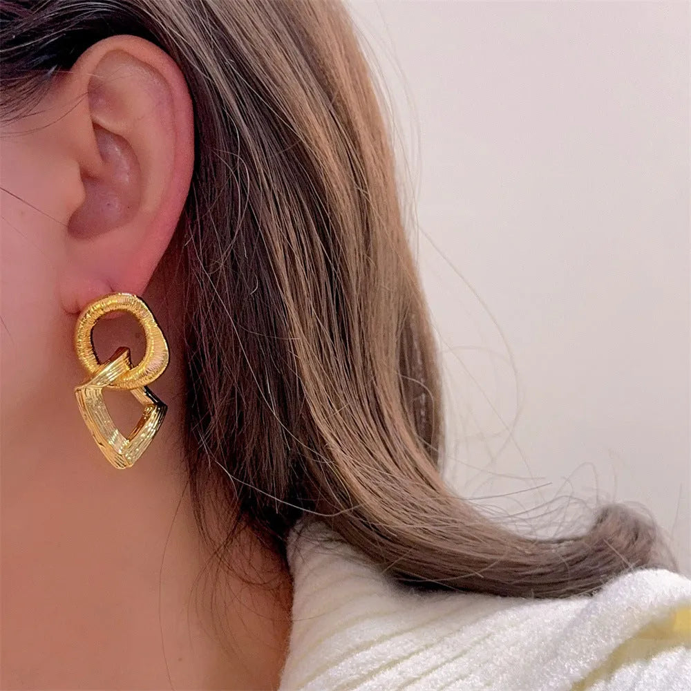 Retro geometric circle pendant earrings in gold or silver tone on a white background.