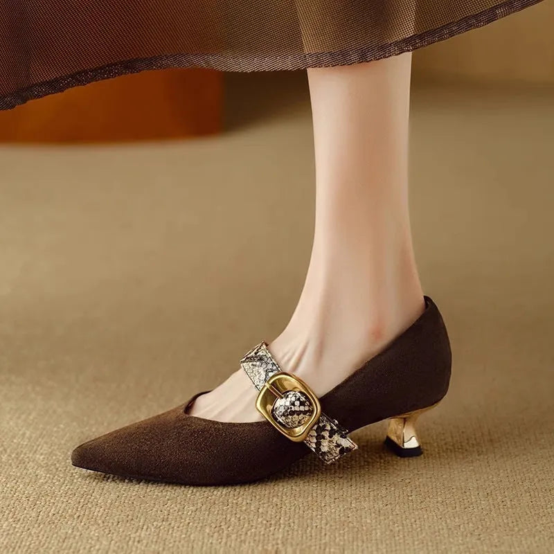 Women's black pointed toe stiletto heels with a buckle strap and a mid-height heel.