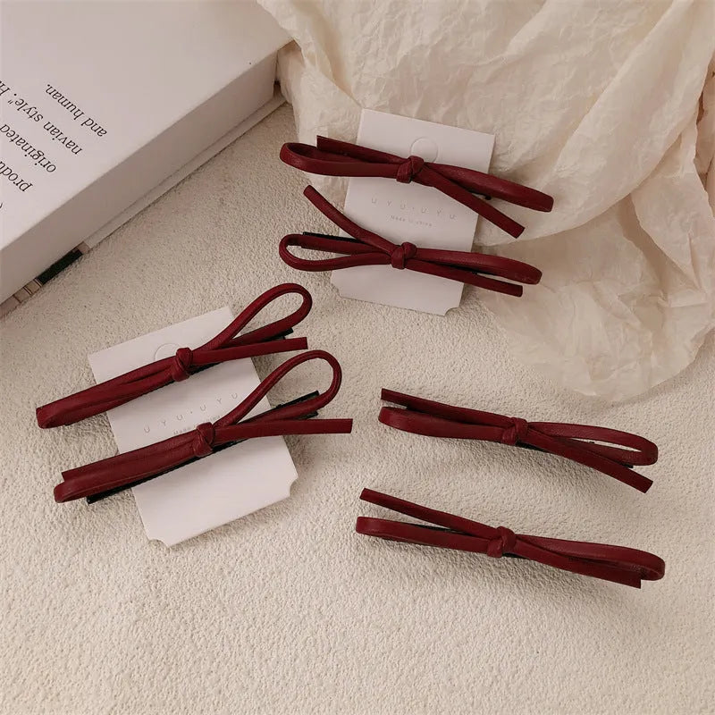 Wine red leather bow hair barrette on hair, showing single clip design