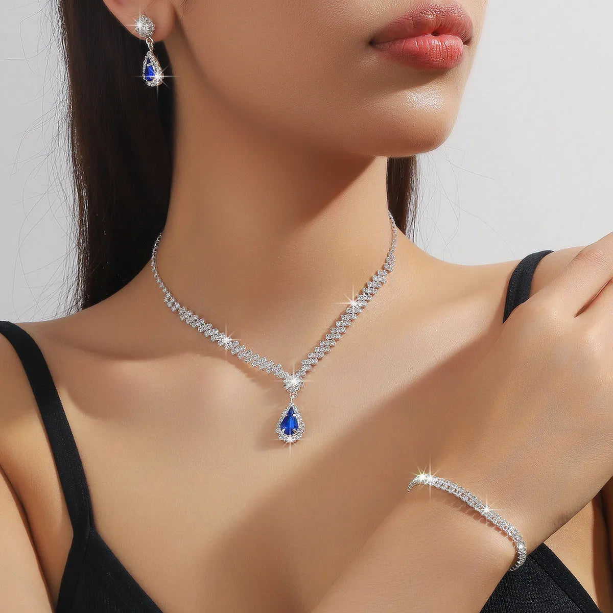 Women's blue claw chain necklace and drop rhinestone earrings from a matching jewellery set.