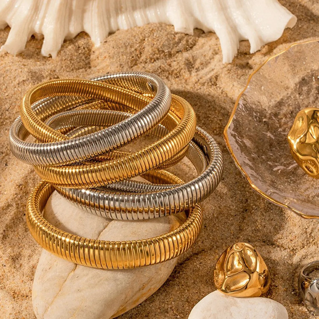 Close-up of a women's elastic titanium steel bracelet featuring a bold vertical stripe ring pattern in a gold tone finish.