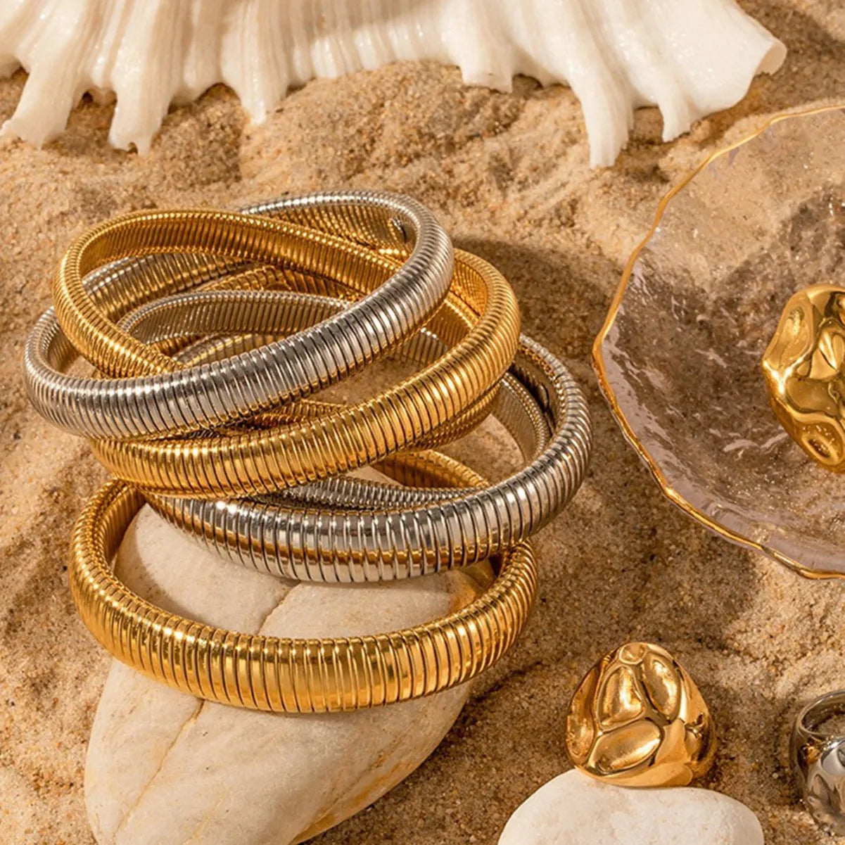 Close-up of a women's elastic titanium steel bracelet featuring a bold vertical stripe ring pattern in a gold tone finish.