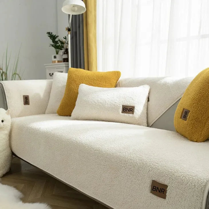 Lambswool machine-washable sofa cover in solid blue colour on a grey sofa