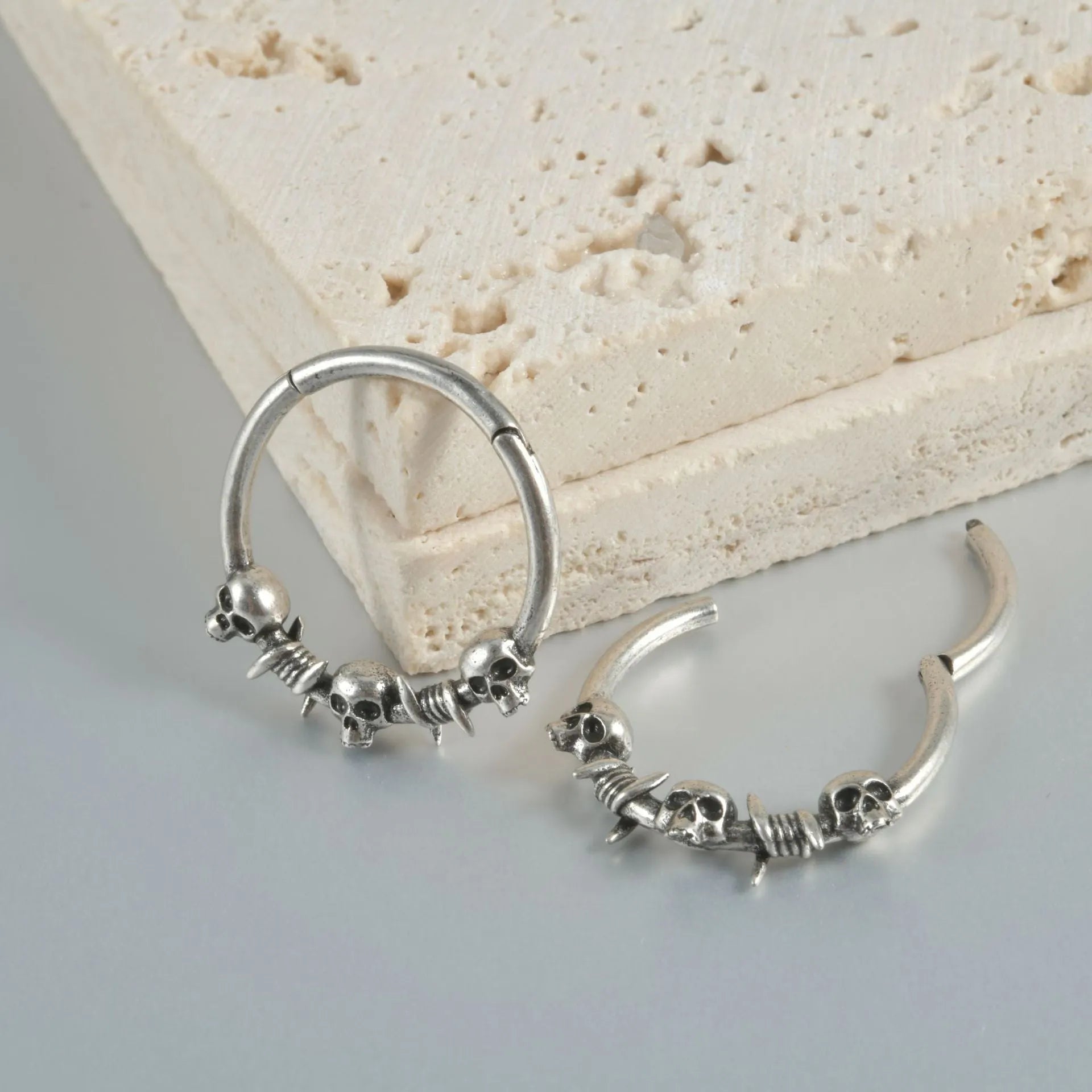 Close-up of copper punk earring with detailed ghost head design in antique silver finish.