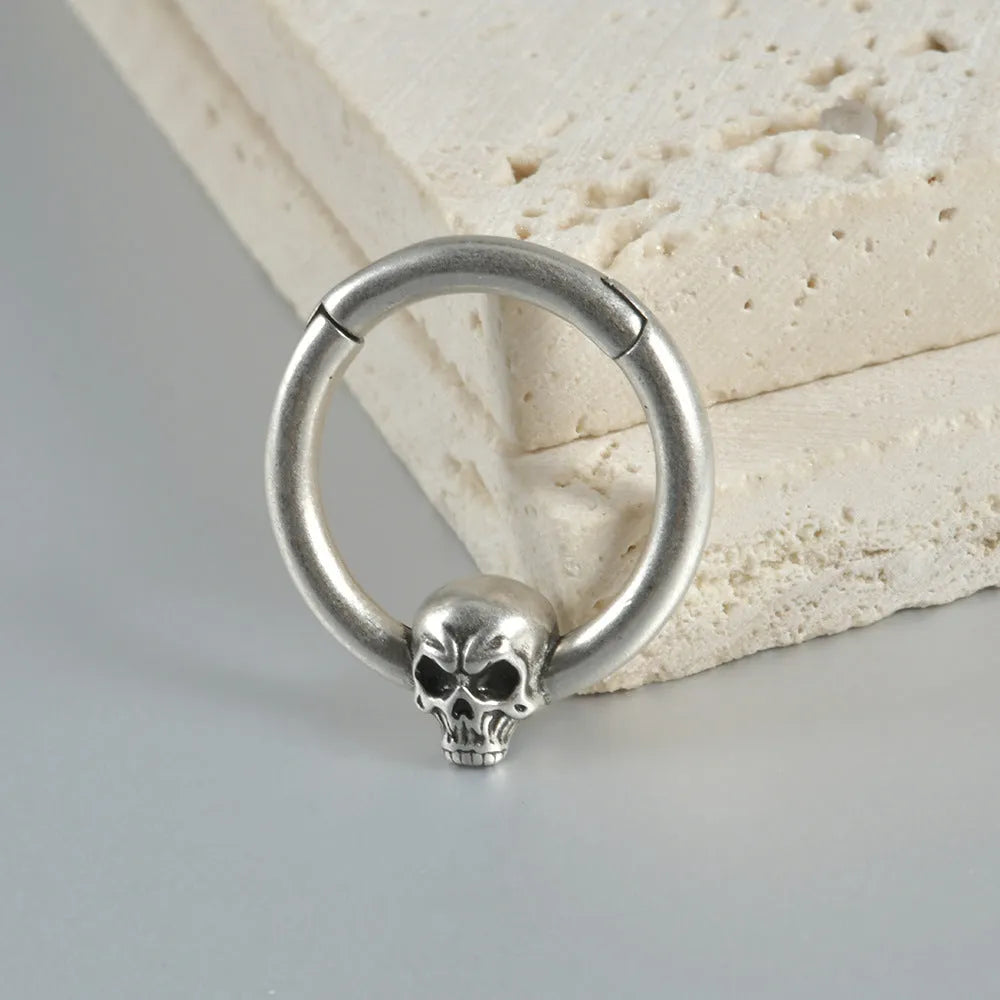 Close-up of copper punk earring with detailed ghost head design in antique silver finish.