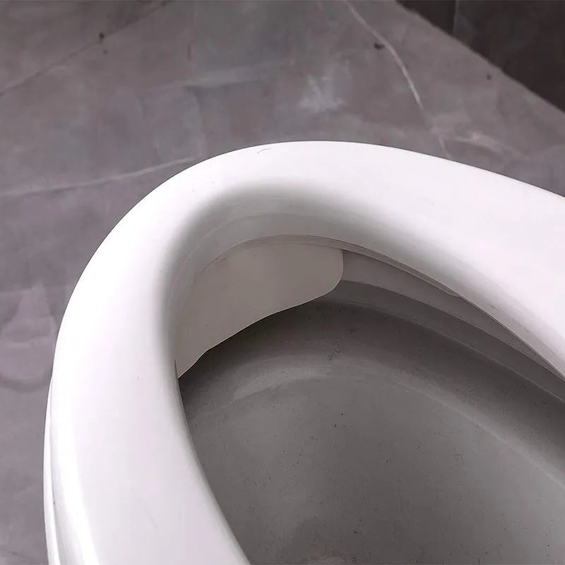 White plastic toilet urine guard for children's toilet training placed on standard toilet seat