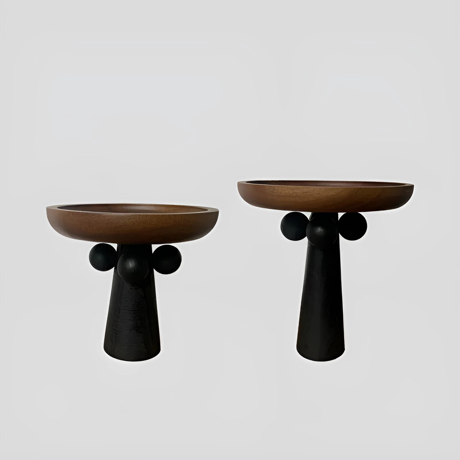 Round natural wooden tray with high legs holding a candle and perfume bottle on a table.