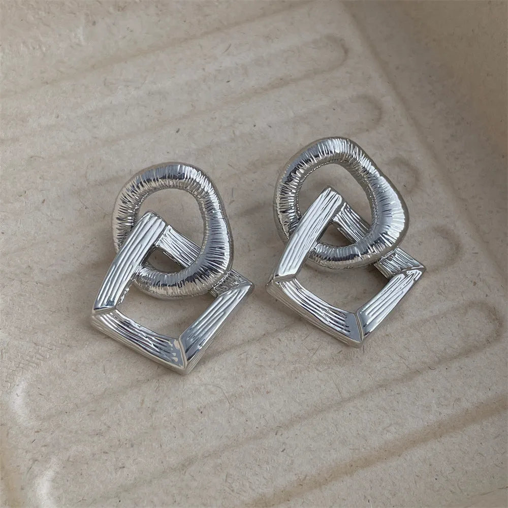 Retro geometric circle pendant earrings in gold or silver tone on a white background.