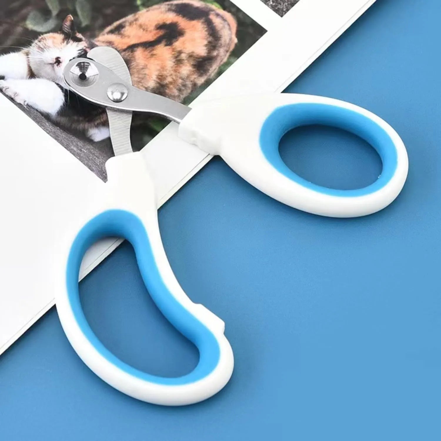 Blue pet nail clippers with circular cutting hole and cushioned non-slip handles on a white background.