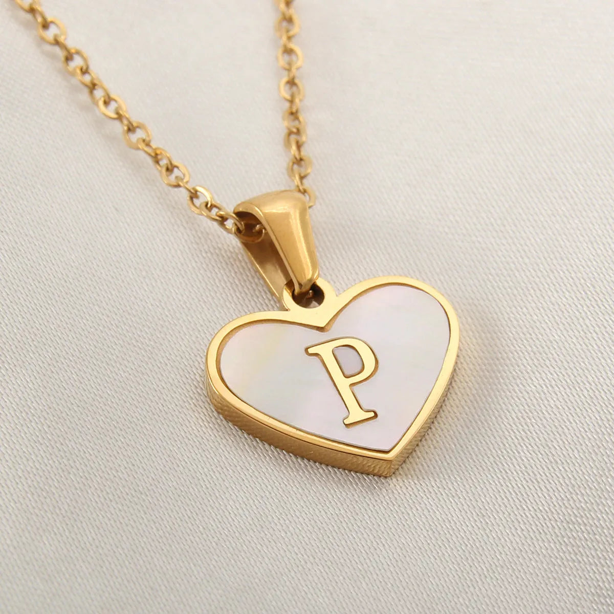 Gold-plated heart necklace with white shell pendant personalised with a letter, on an adjustable chain.