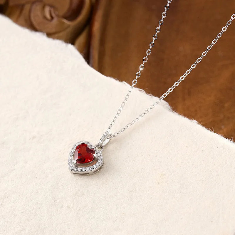 Women's sterling silver necklace with heart-shaped pendant containing natural gemstone on adjustable cross chain