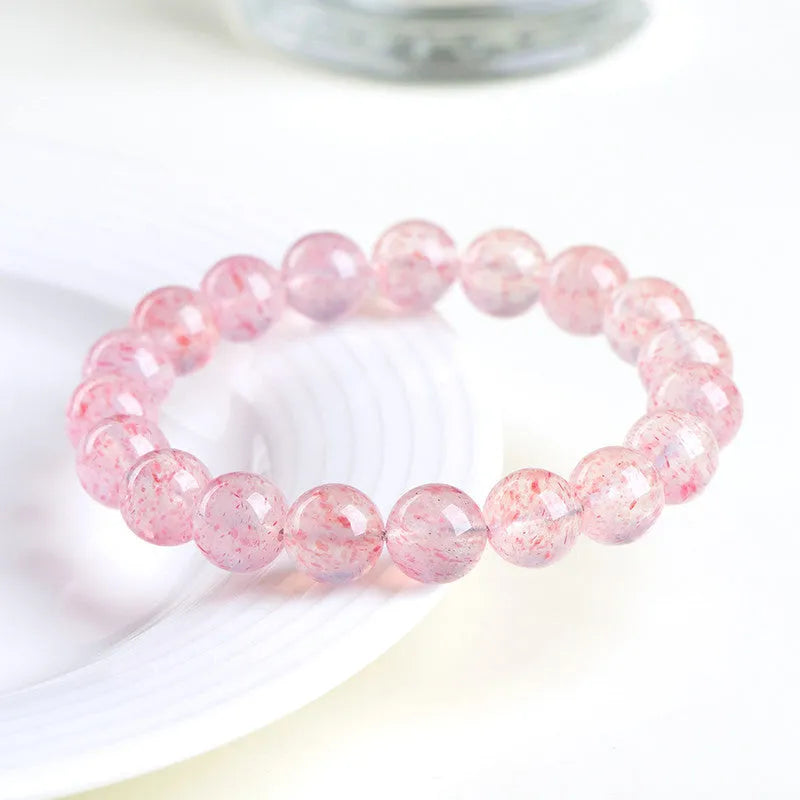Natural strawberry quartz crystal bracelet with 19 round geometry beads on a white background.