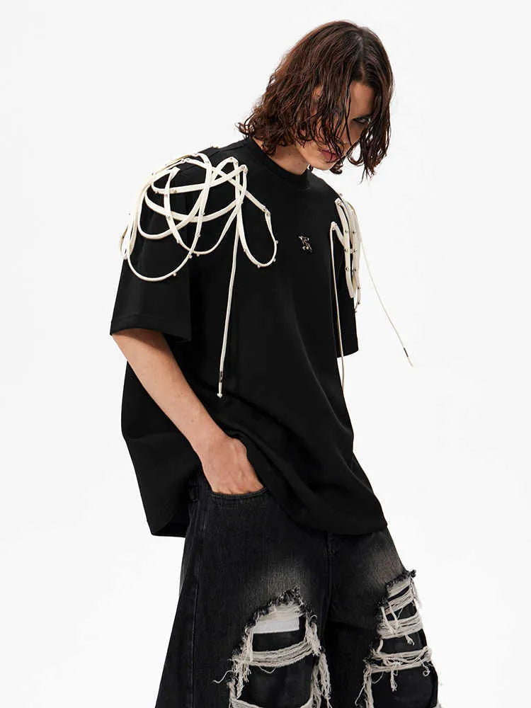 Black loose fit short sleeve T-shirt with ribbon and rivet decorated padded shoulders.
