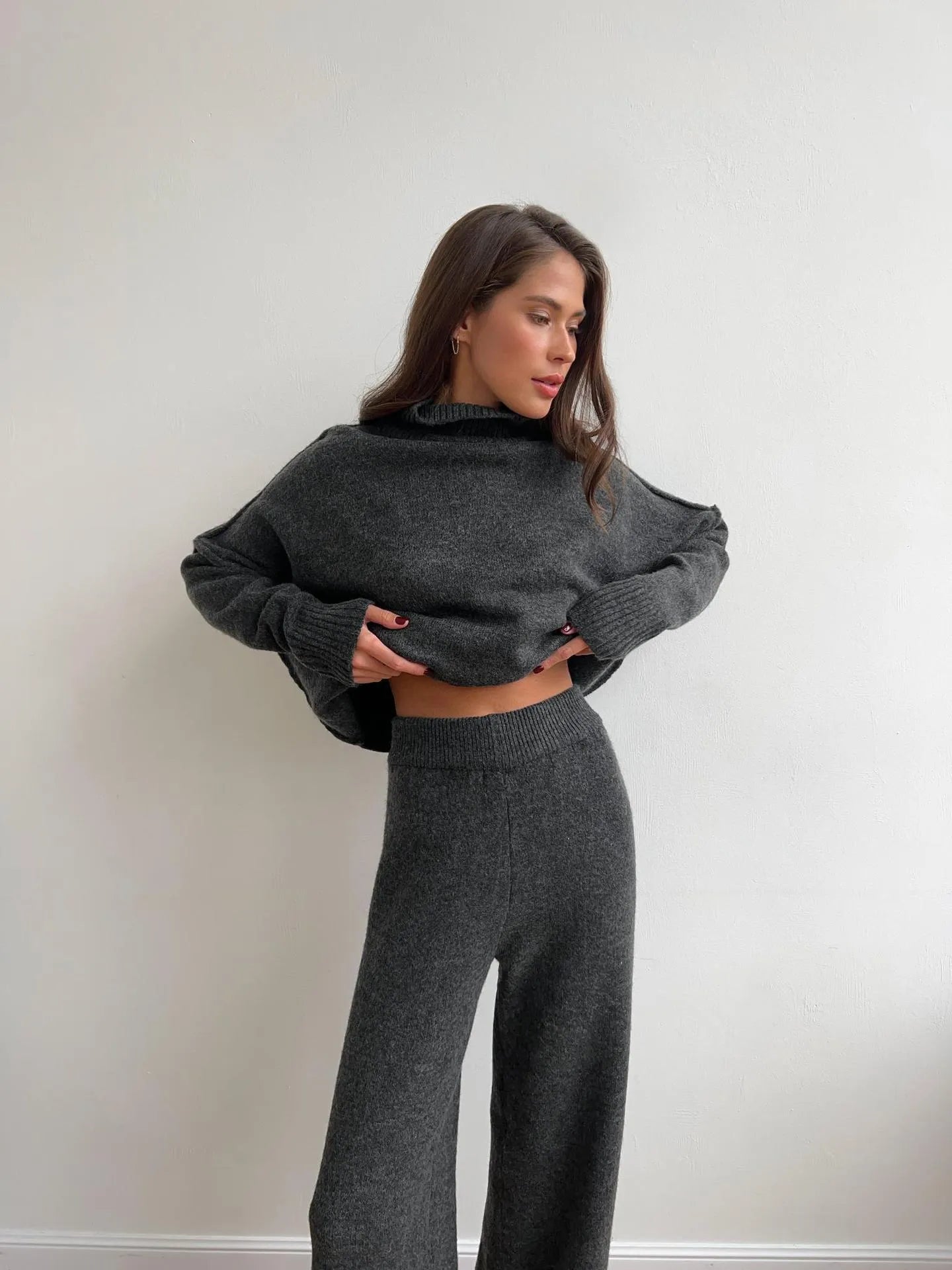 Women's dark grey knit co-ord suit with side-slit sweater and matching trousers laid flat.