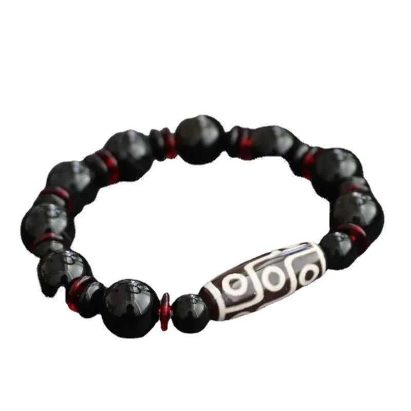 Close-up of a hand-woven black agate bracelet with 11mm geometric beads featuring traditional dzi patterns.