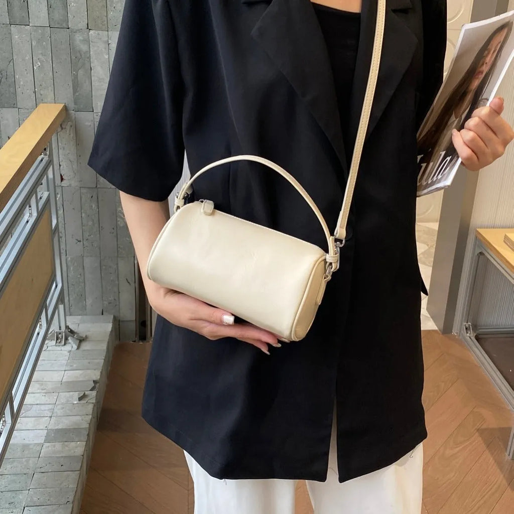Soft genuine leather cylindrical crossbody bag for mobile phones, shown in a street style with visible stitching.