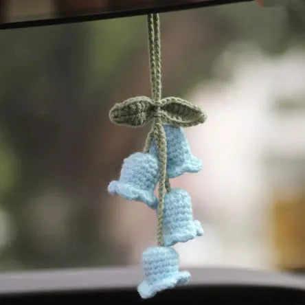 Green and white knitted wool car plant decoration with hanging rope on car dashboard