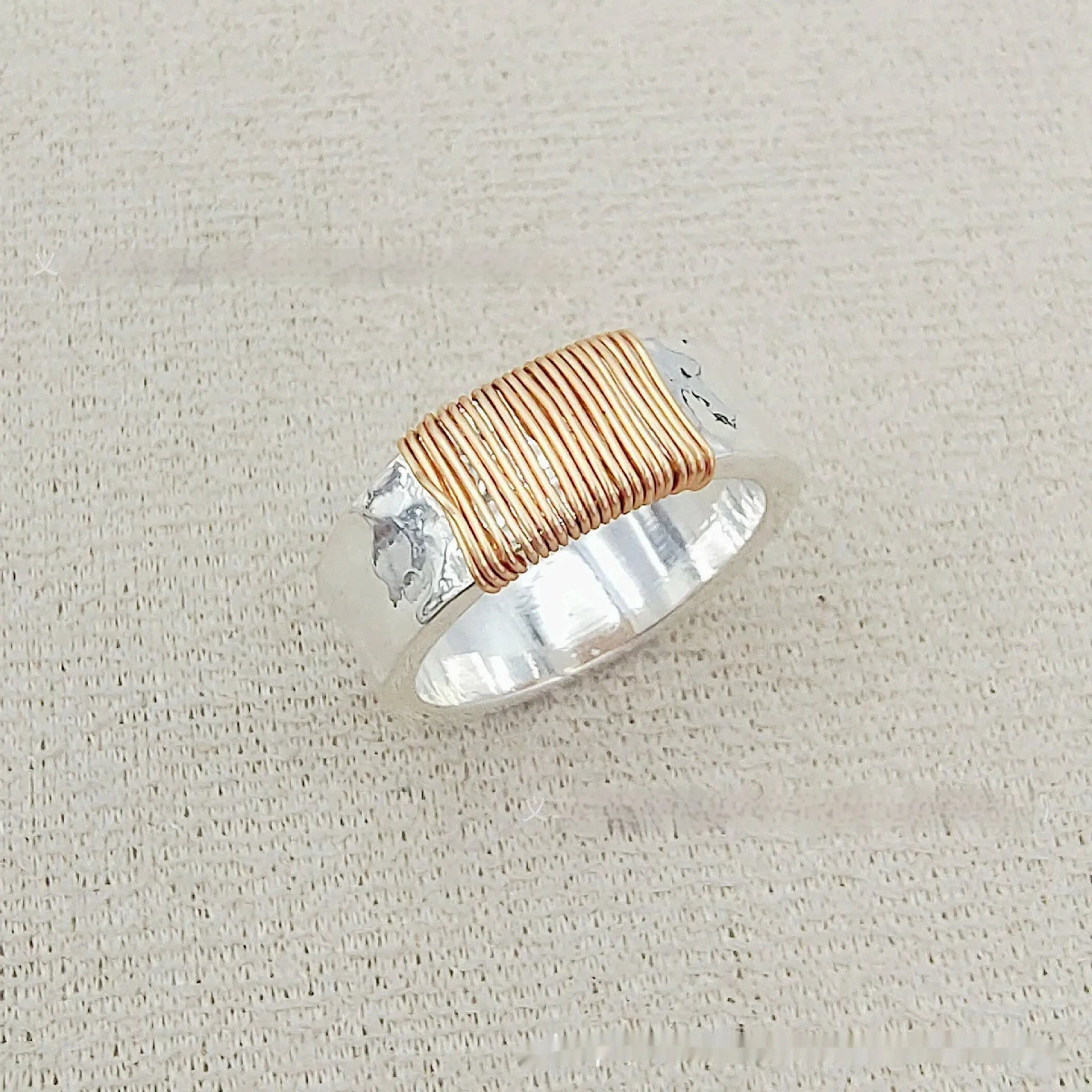 Copper wide face ring with irregular coil design in silver-gold colour.