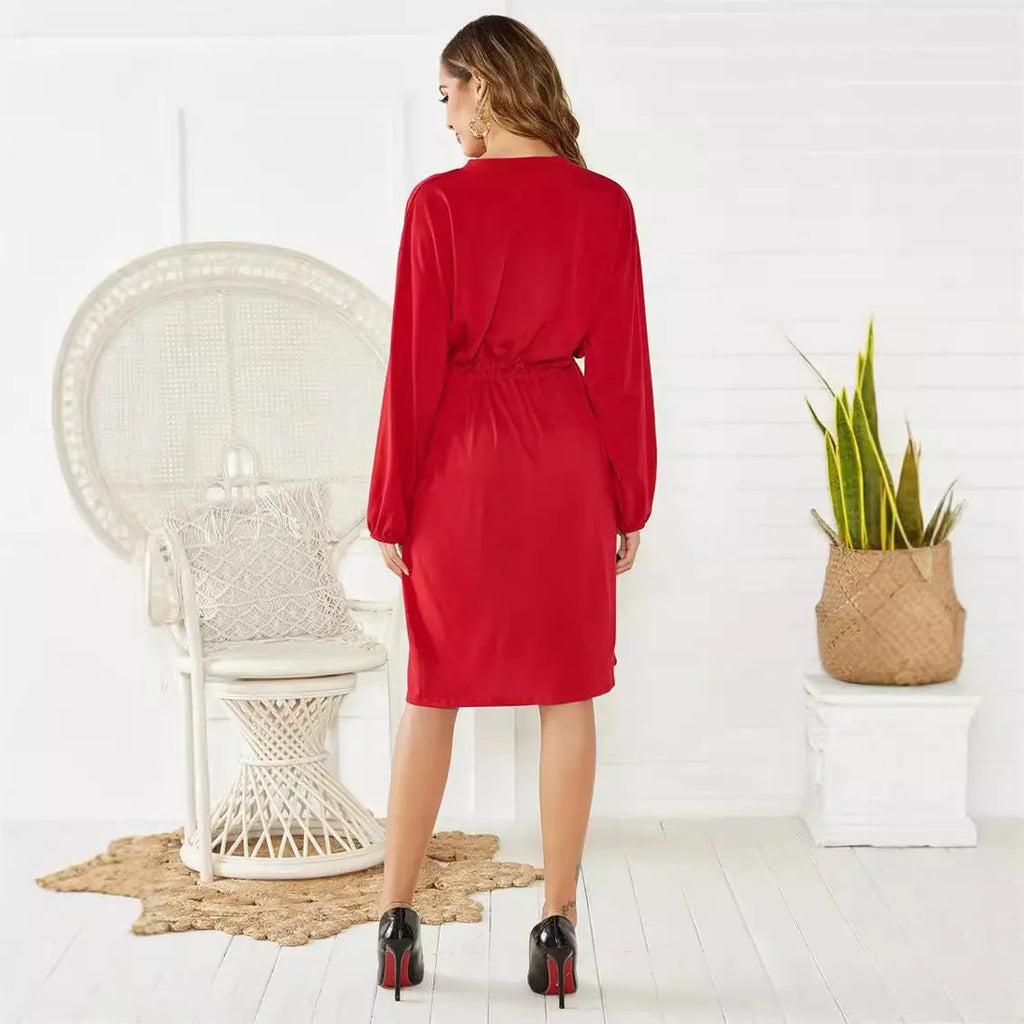 A woman wearing a solid colour midi dress with an elastic waist, long sleeves, and a loose belt.