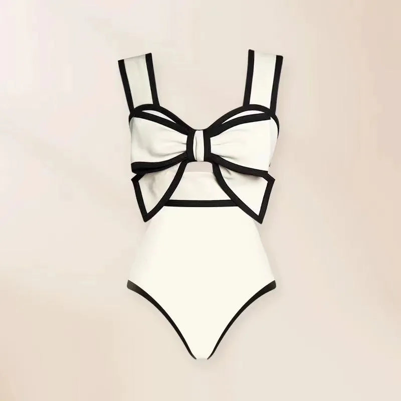 Women's black one-piece swimsuit with a white bow-accented beach dress cover-up skirt.