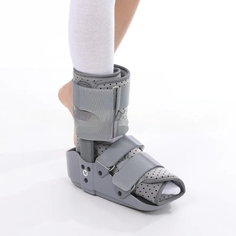 Grey Achilles tendon rehabilitation boot with aluminium side struts and a rubber sole, shown on a foot.