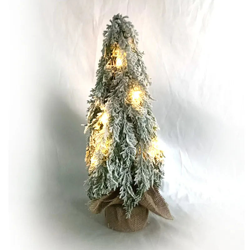 Small white artificial Christmas tree with snowy textured branches and built-in lights on a desktop