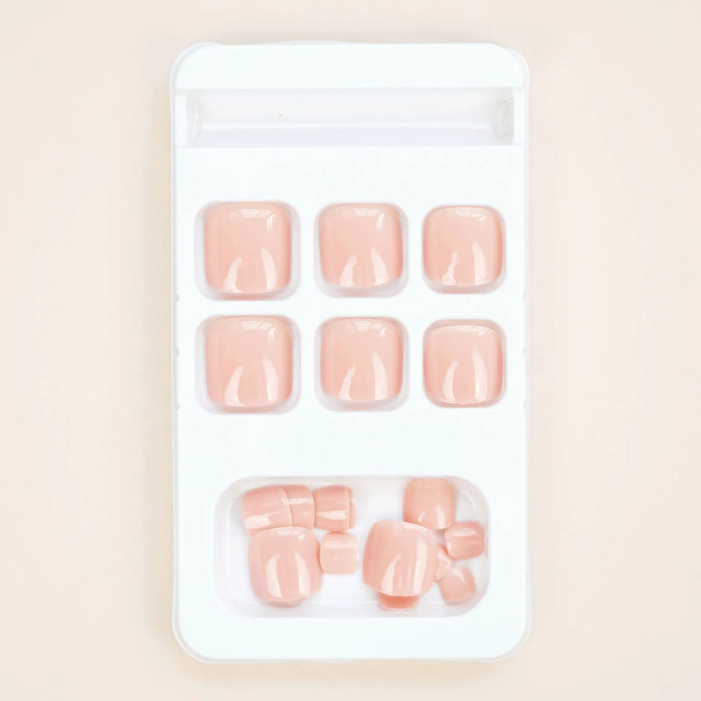 Pack of finished skin colour false toenails and a tube of adhesive glue for nail art.