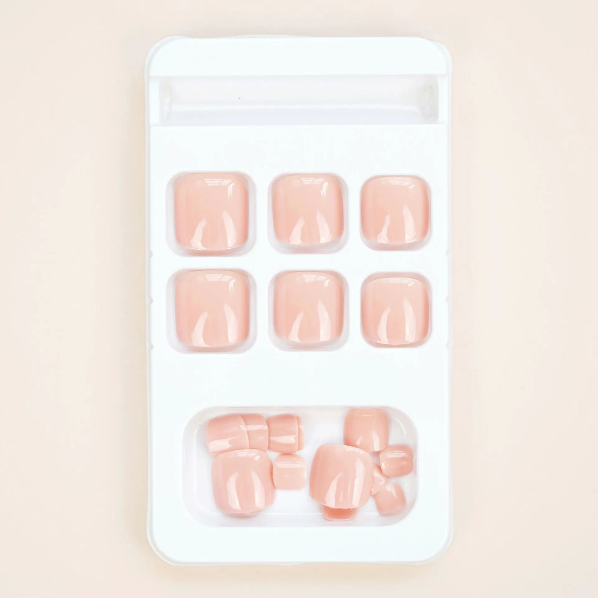 Pack of finished skin colour false toenails and a tube of adhesive glue for nail art.