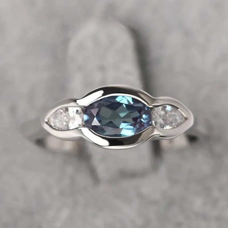 Geometric ellipse women's ring with a central zircon stone and white gold plating.