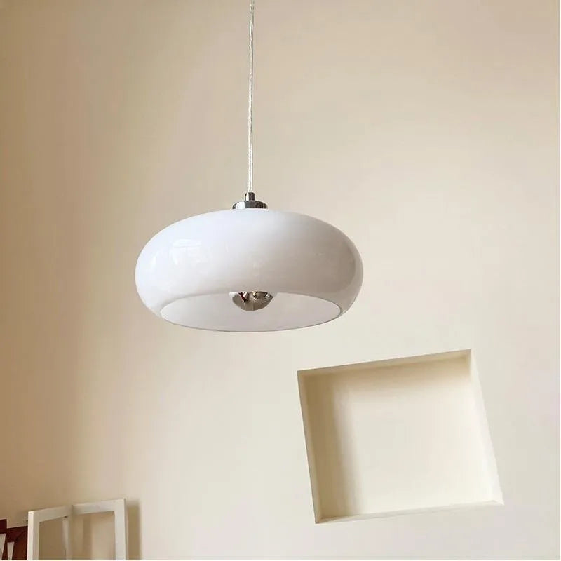 Three-headed Bauhaus pendant light with milky white glass egg tart shades hanging from a ceiling.