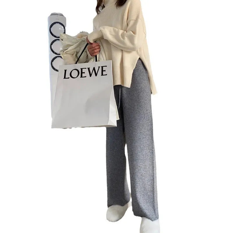 Woman wearing high waist cream white knitted wide-leg trousers with a straight, drooping mopping cut.