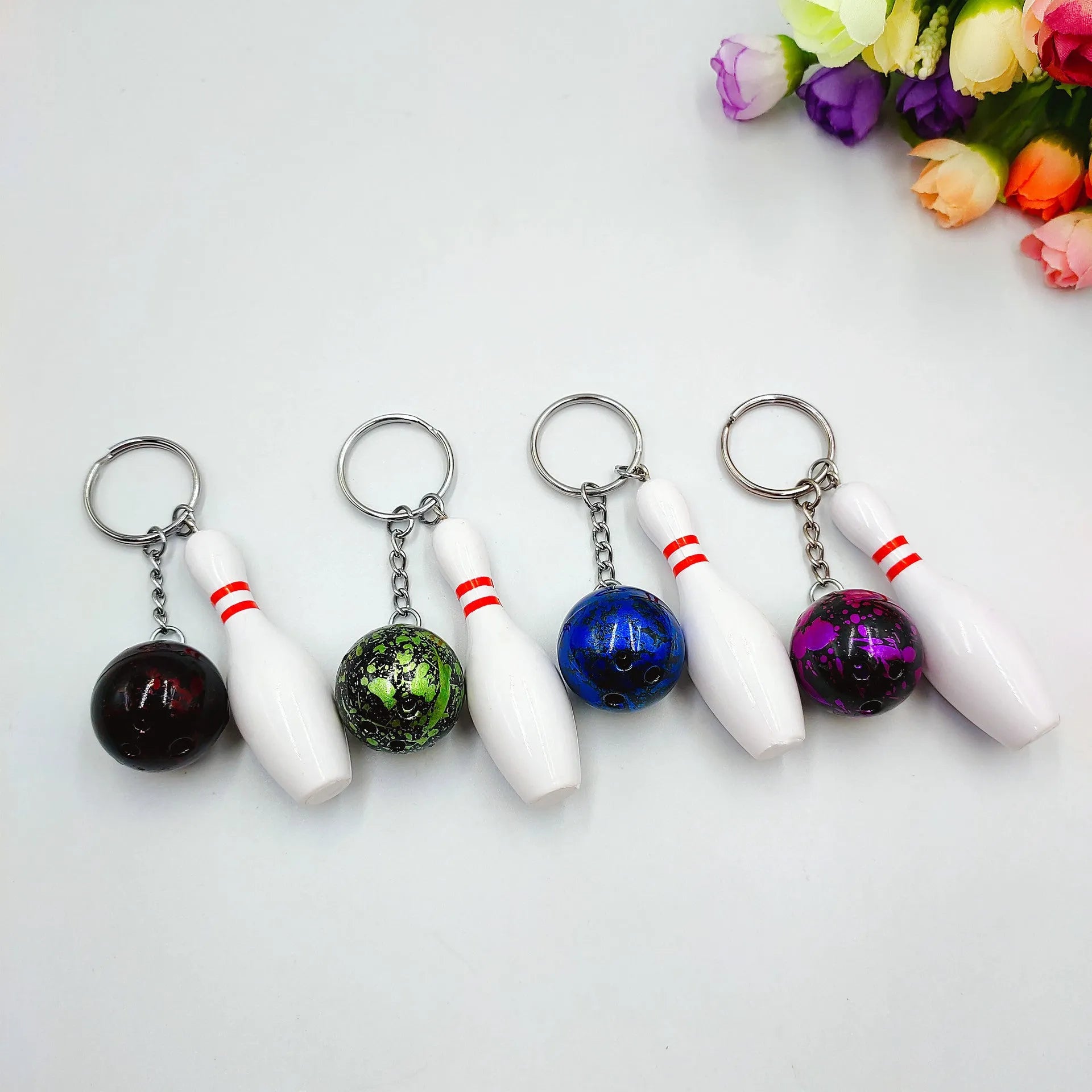 Mini sports bowling keychain pendant in PVC metal, shown in dark red, blue, purple, and green colour options.