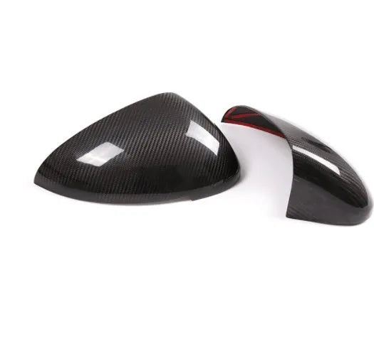 Glossy black true carbon fibre rearview mirror cover for Porsche Macan on a white background