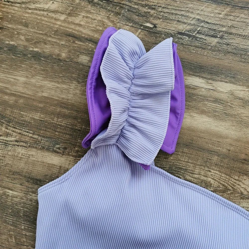 Women's solid colour single-shoulder two-piece swimsuit with high-waist bottoms on a mannequin.