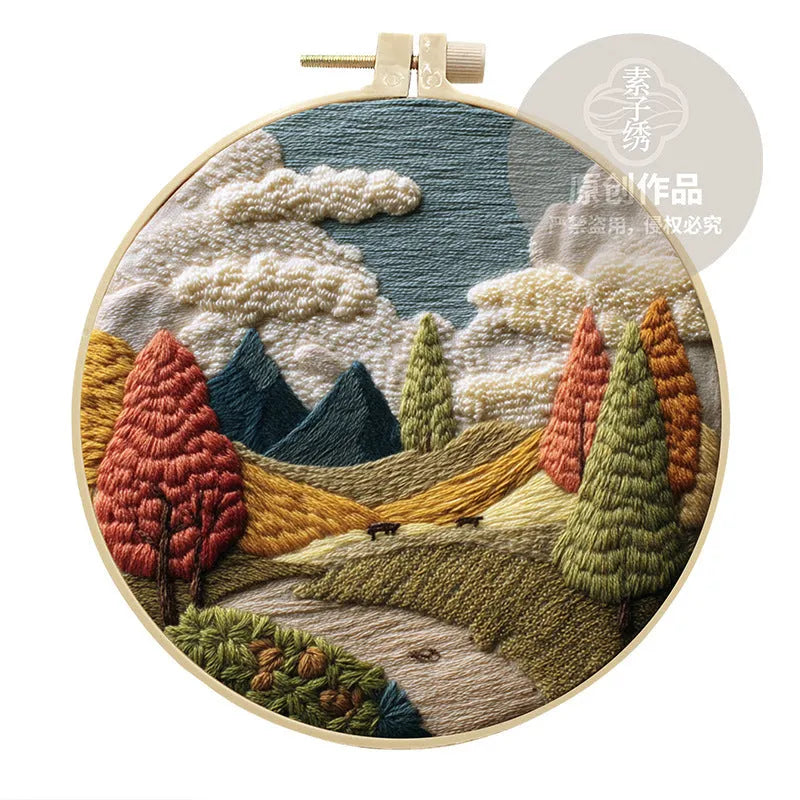 DIY landscape embroidery kit with cotton fabric, bamboo frame, threads and needles arranged for crafting
