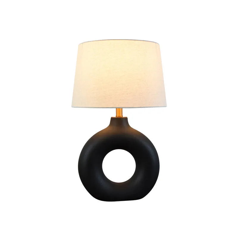 Japanese-style white ceramic table lamp with a button switch on a wooden desk.