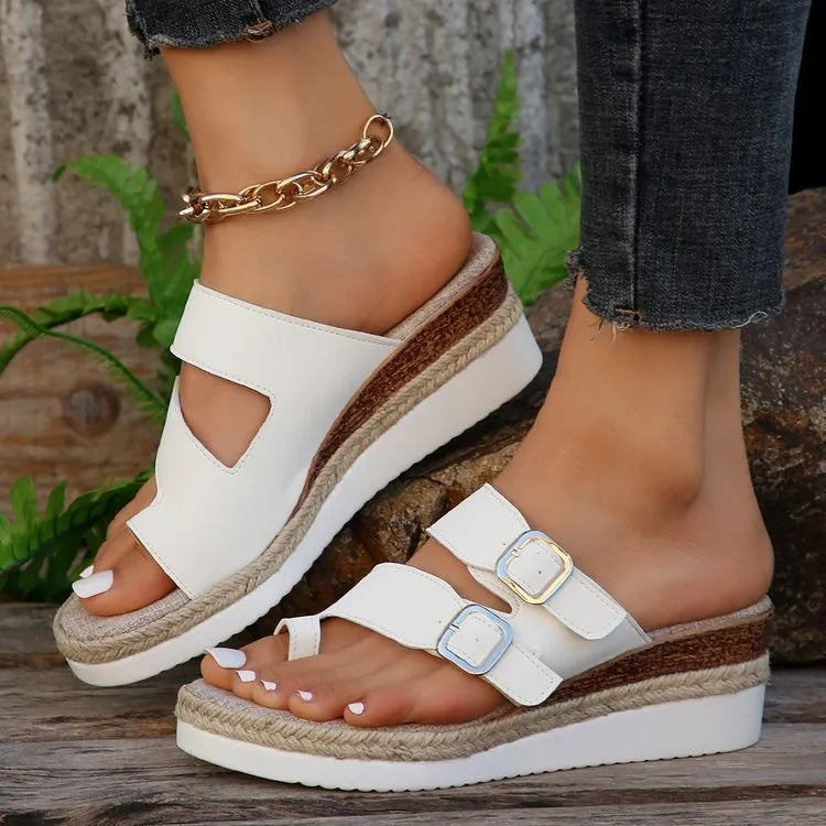 White patent leather wedge sandals with woven finger fit design and peep toe on a rubber sole.