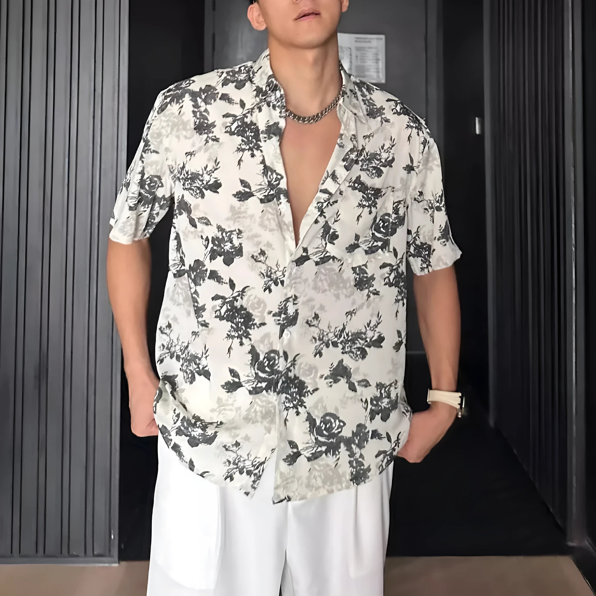 Man wearing a loose black floral print short sleeve casual shirt with a cardigan style open front.