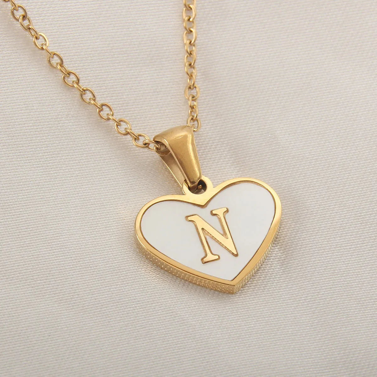 Gold-plated heart necklace with white shell pendant personalised with a letter, on an adjustable chain.