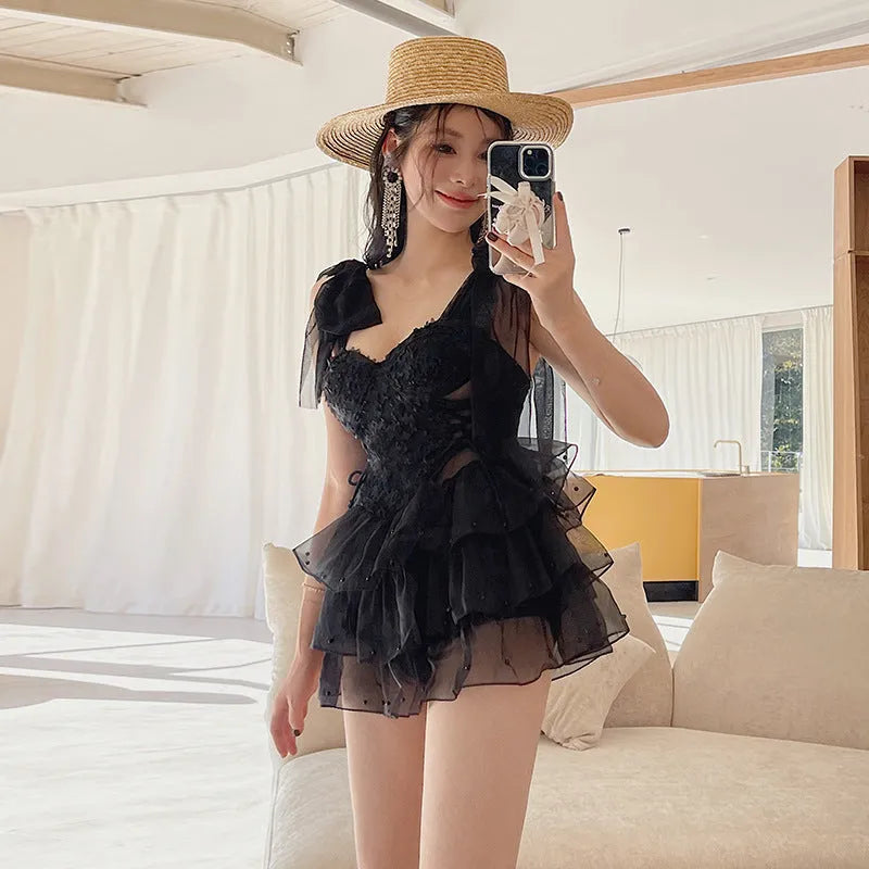 Black conservative one-piece swimsuit with gathered chest detail, sleeveless design.