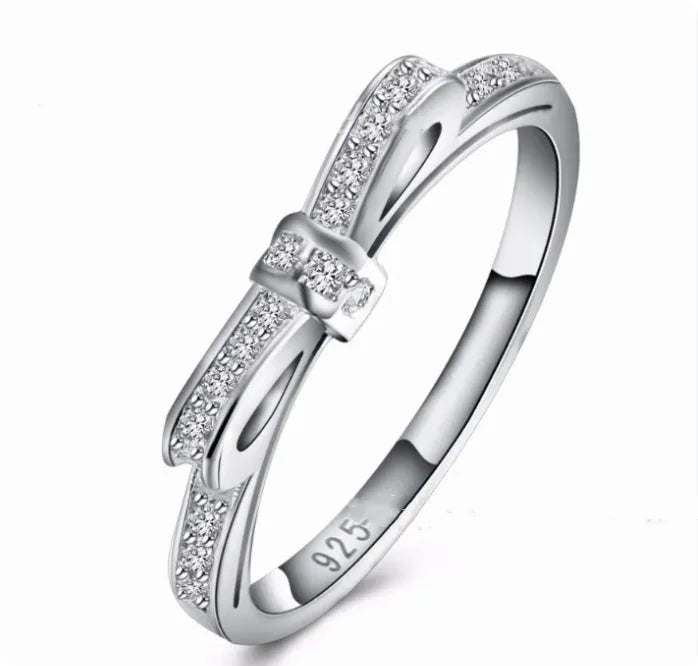 Silver couple style ring with a rhinestone and zircon crystal bow design on a finger.