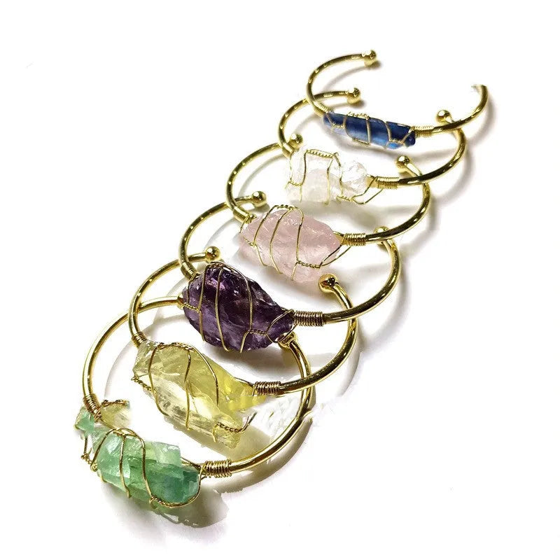 Geometric natural crystal bracelet with gold metal winding on a wrist.