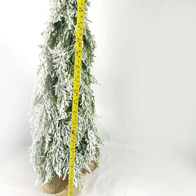 Small white artificial Christmas tree with snowy textured branches and built-in lights on a desktop