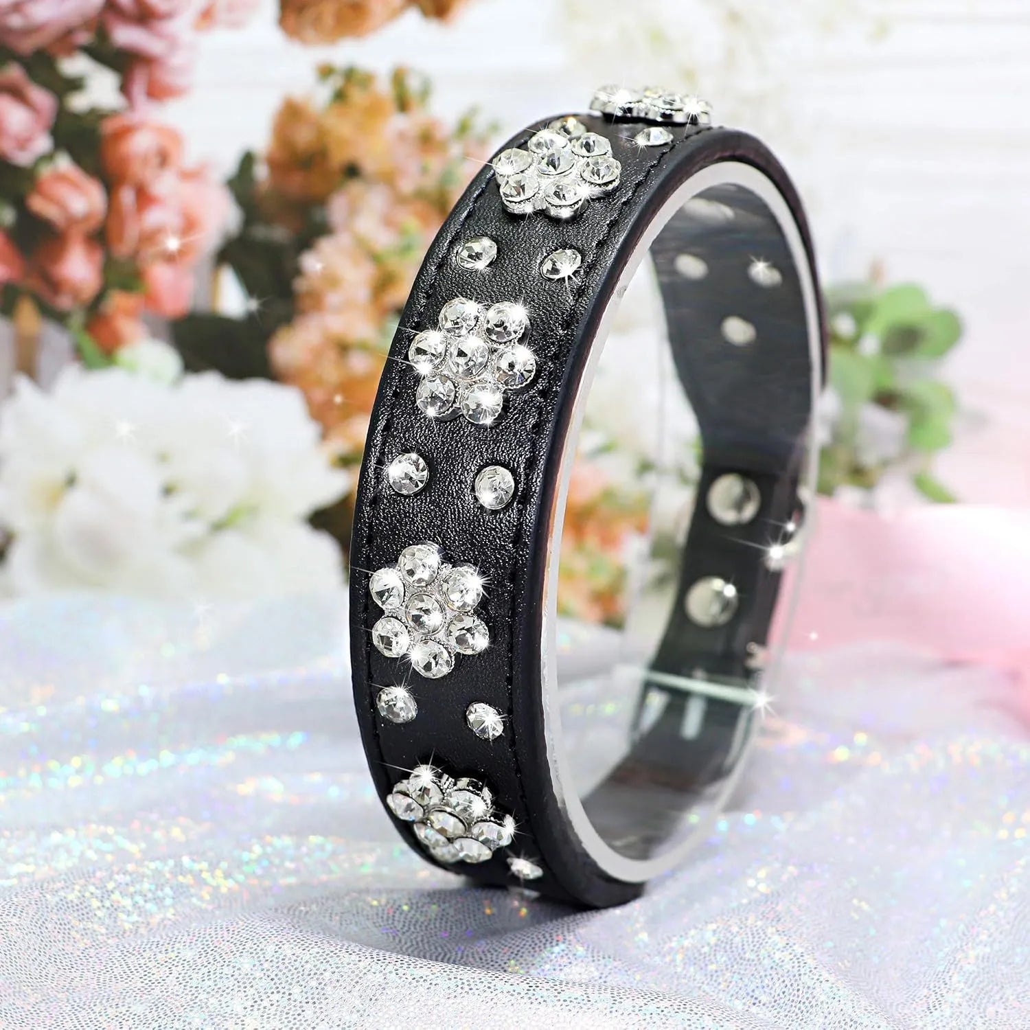 Close-up of a pink PU leather dog collar with silver rhinestone flowers and studs, showing the metal D-ring.