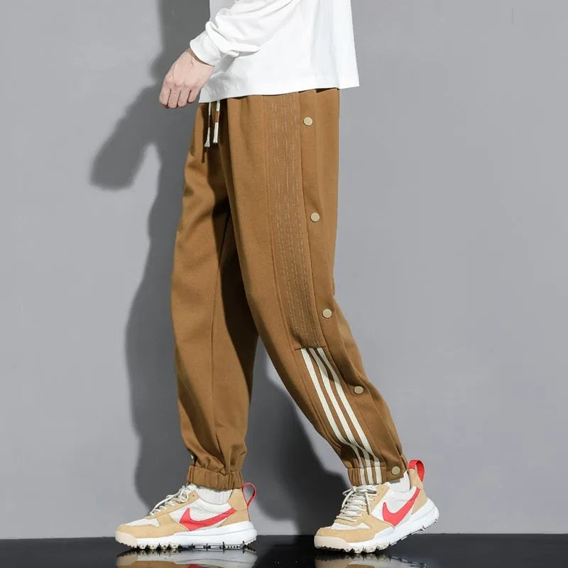 Man wearing loose grey cotton blend sweatpants with ankle ties and a drawstring waist.